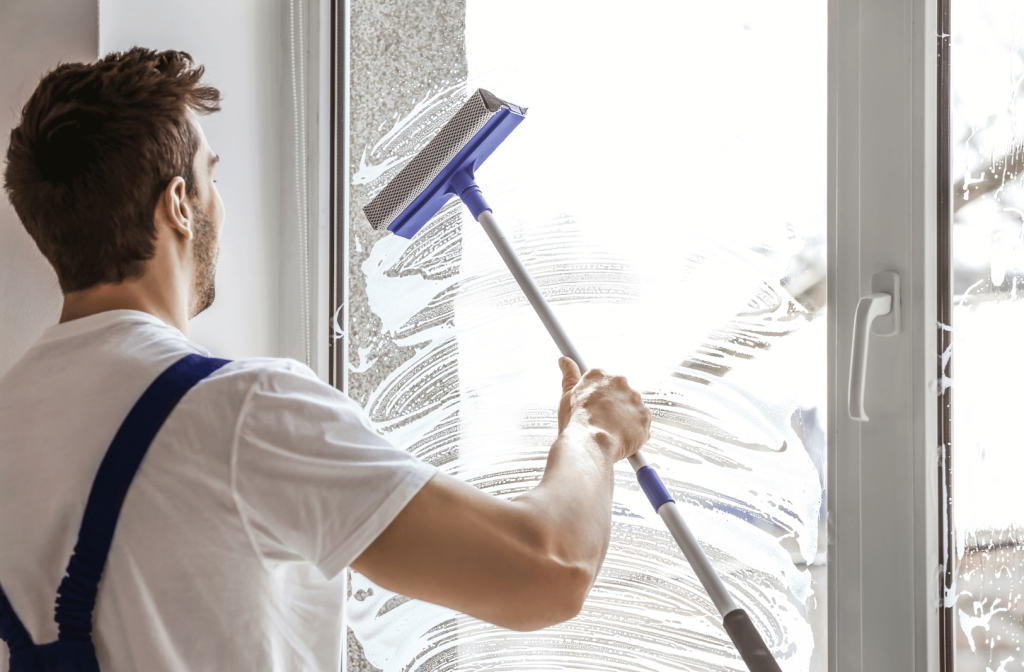 Man in white cleaning a window