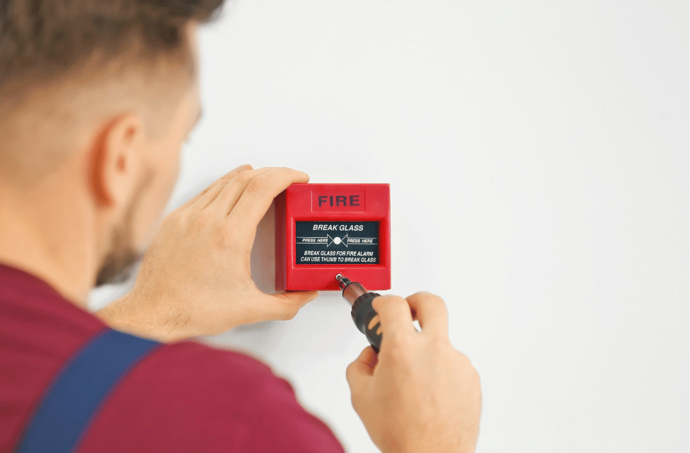 man fitting a fire alarm with a screwdriver
