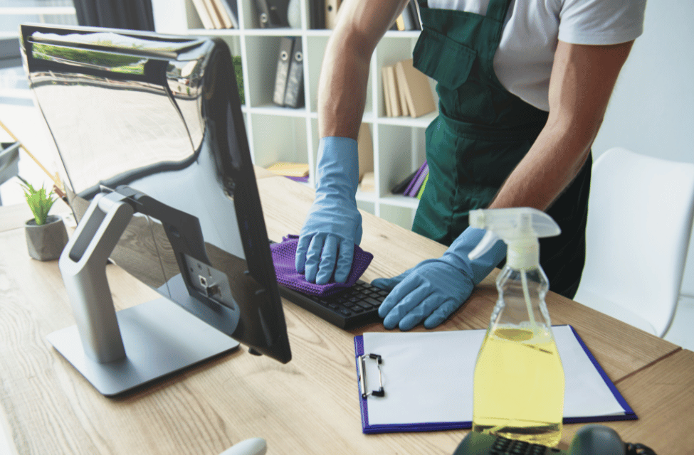 A professional London cleaner disinfecting a keyboard and desk